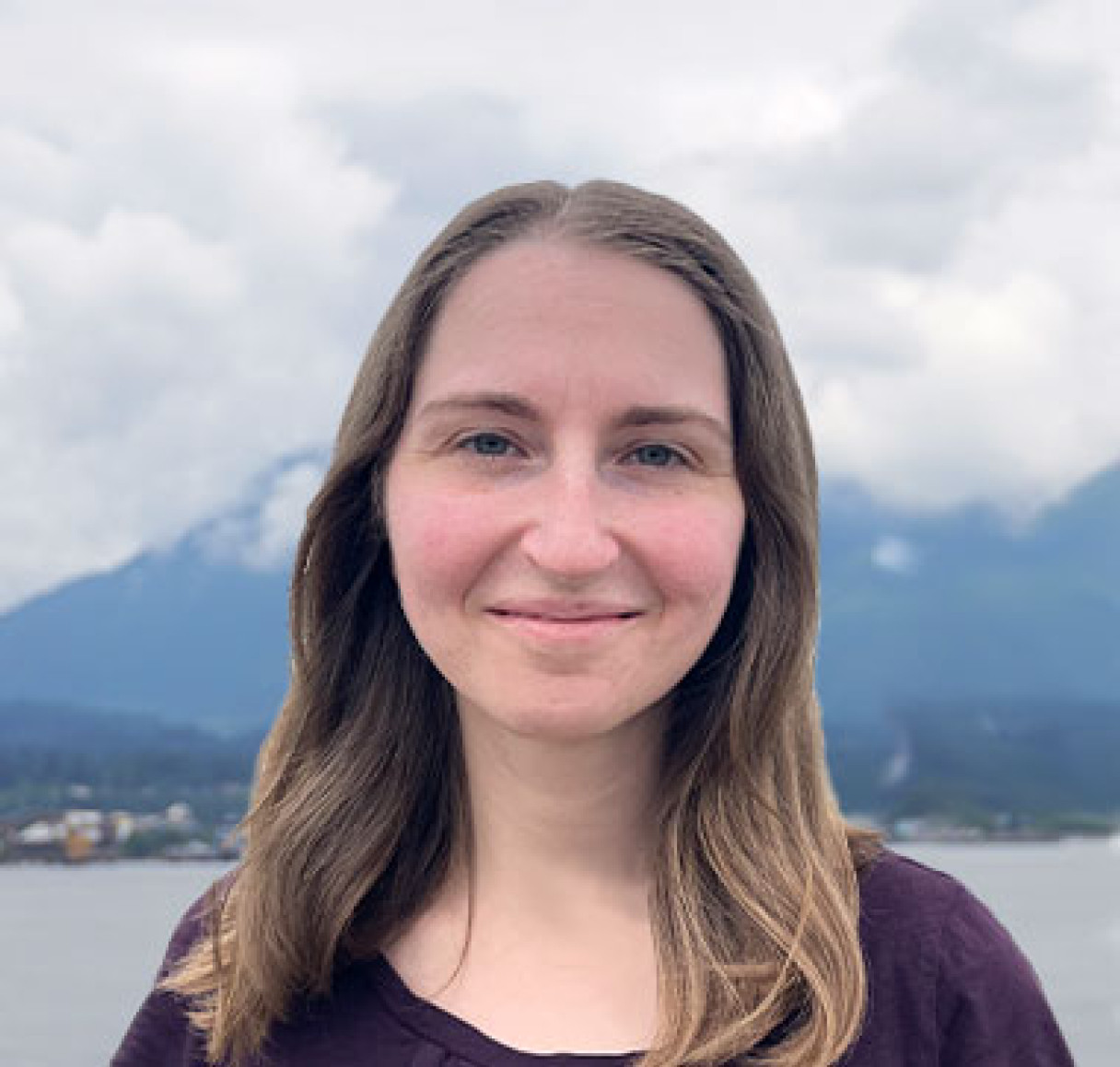 Photo of a woman with shoulder-length brown hair in front of mountains