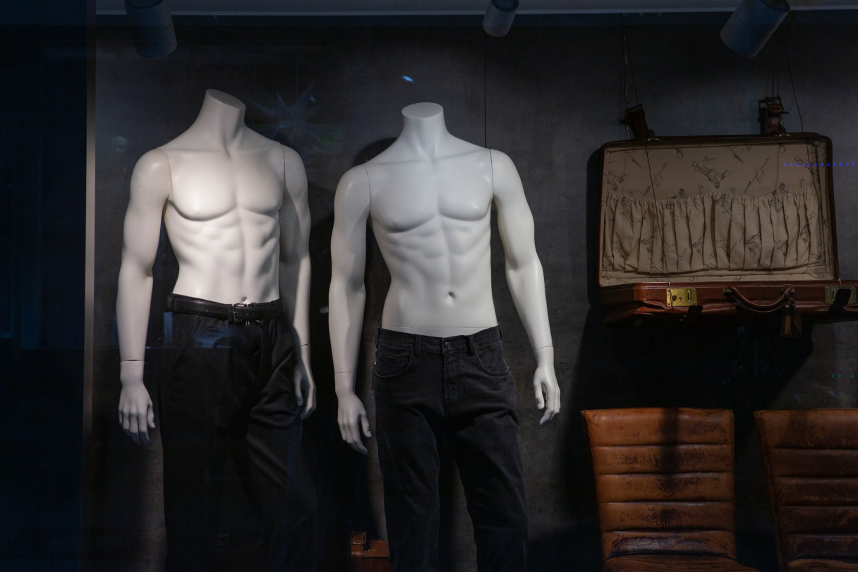 Two male mannequins with no heads wearing only pants